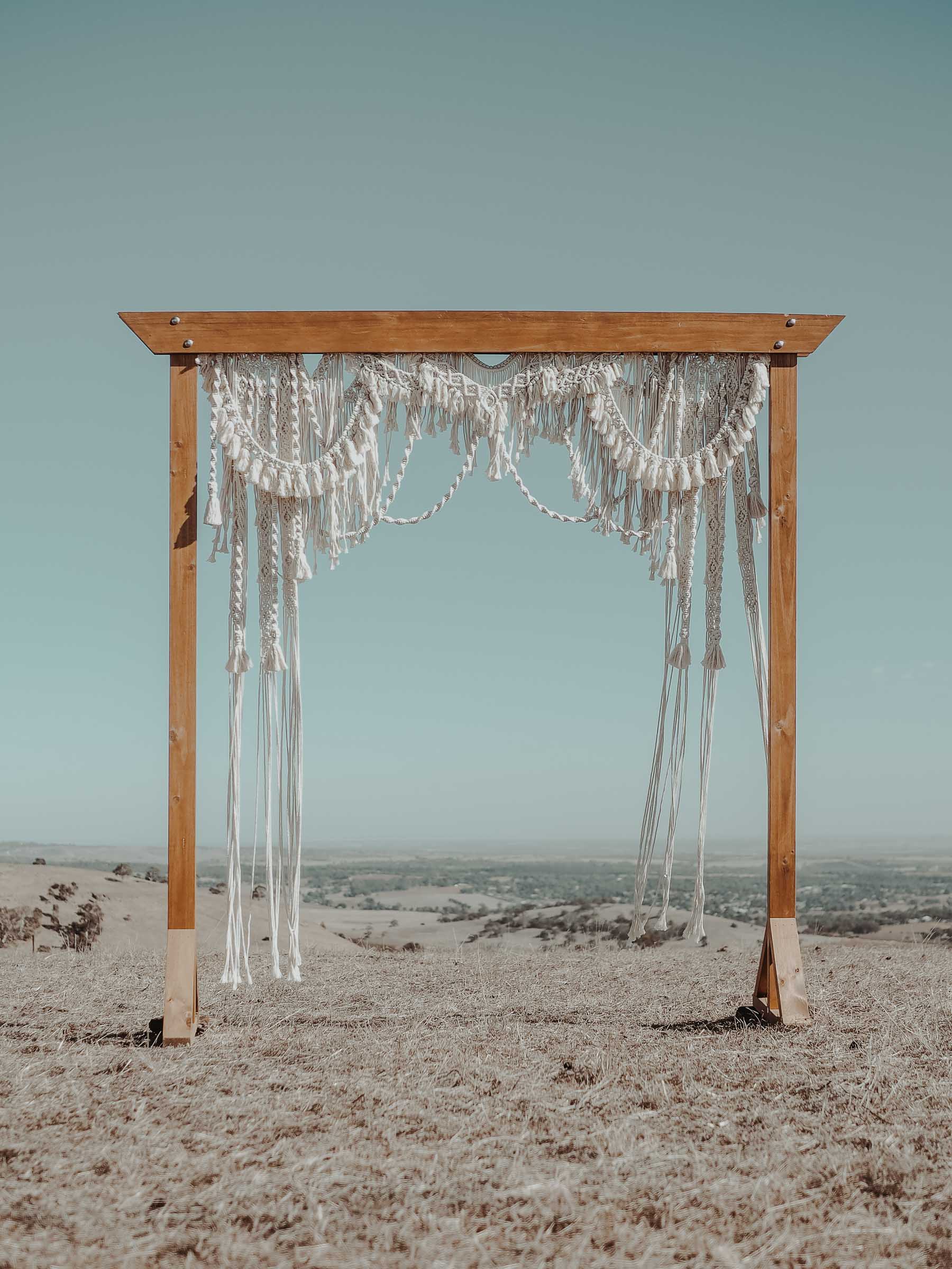Rustic wooden arbour with a handmade macrame arch backdrop