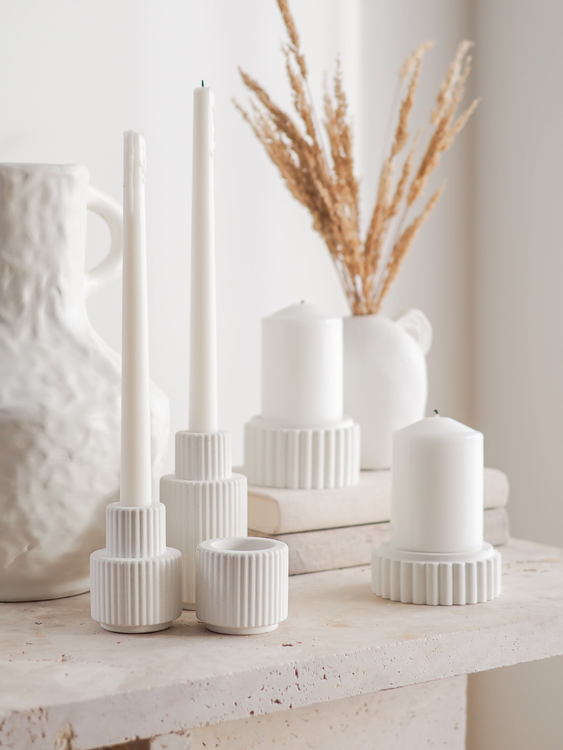 Palmer and Preston candle holders displayed with a natural irregular vase and a small vase with pampas on a stack of linen books