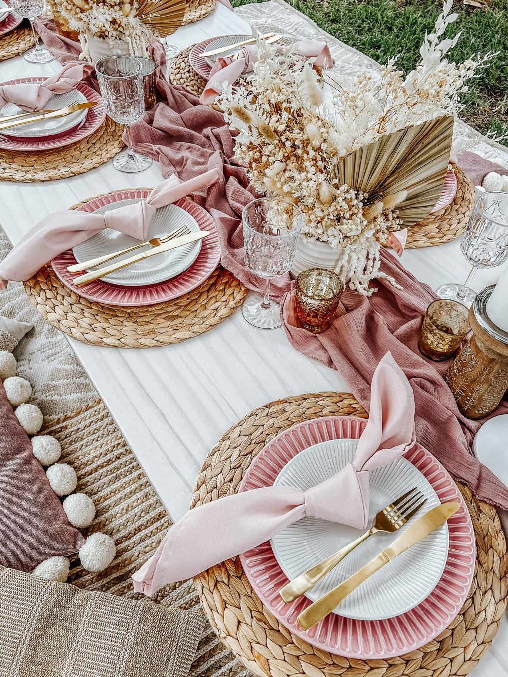 Baby pink picnic close up of table settings with pink ridged plates, pink table runner, hyacinth placemats, and pink napkins