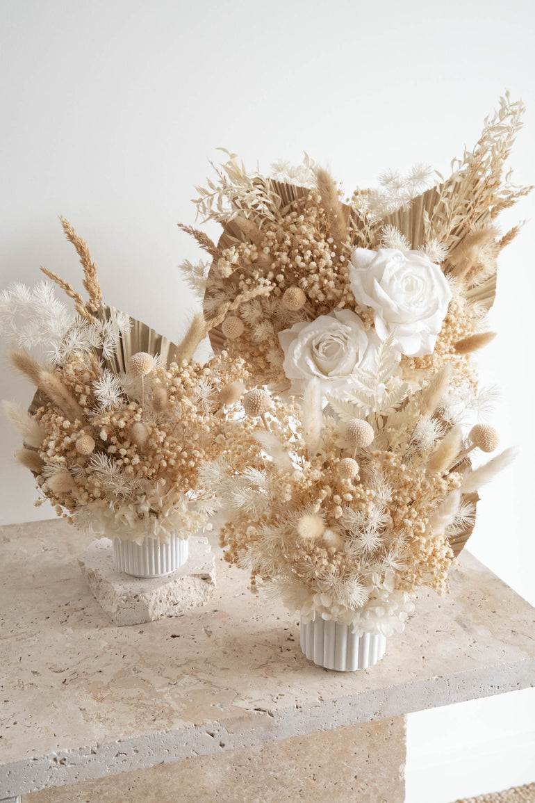 Set of three natural boho dried floral arrangements on a travertine table