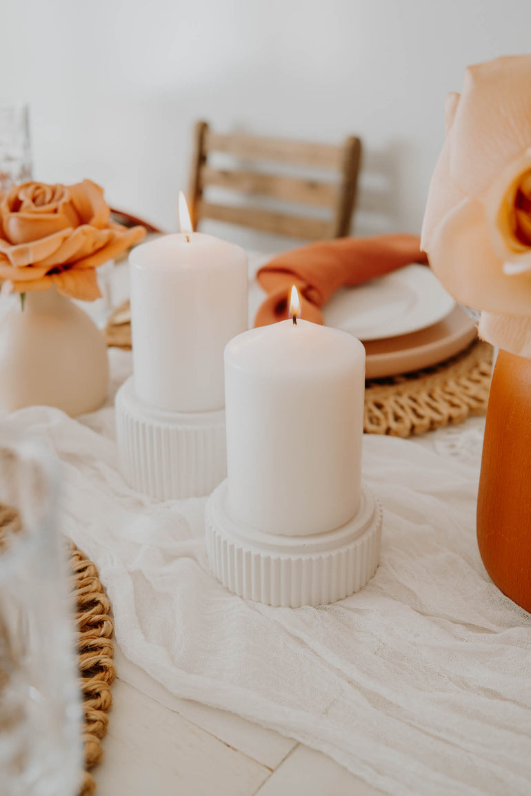 Large and small Mason candle holders displayed as centrepieces on a table with burnt orange roses in bud vases