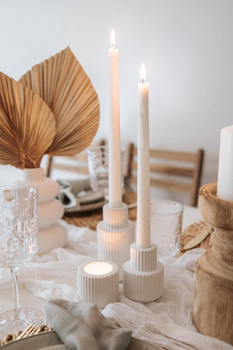 Palmer candle holders with lit candles displayed with dried palms and wooden candle holders 