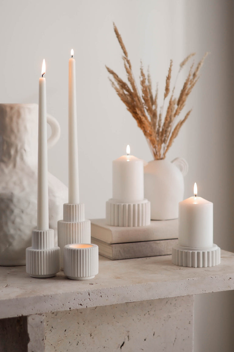 Palmer ribbed concrete candle holders with our Preston pillar candle holders displayed with lit candles on a travertine table