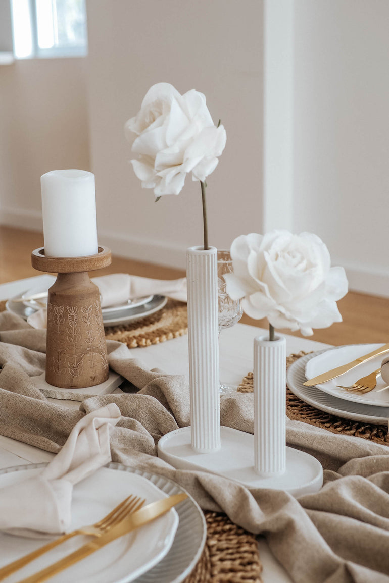 Sterling single stem vase displaying two single white rose on a taupe linen table runner
